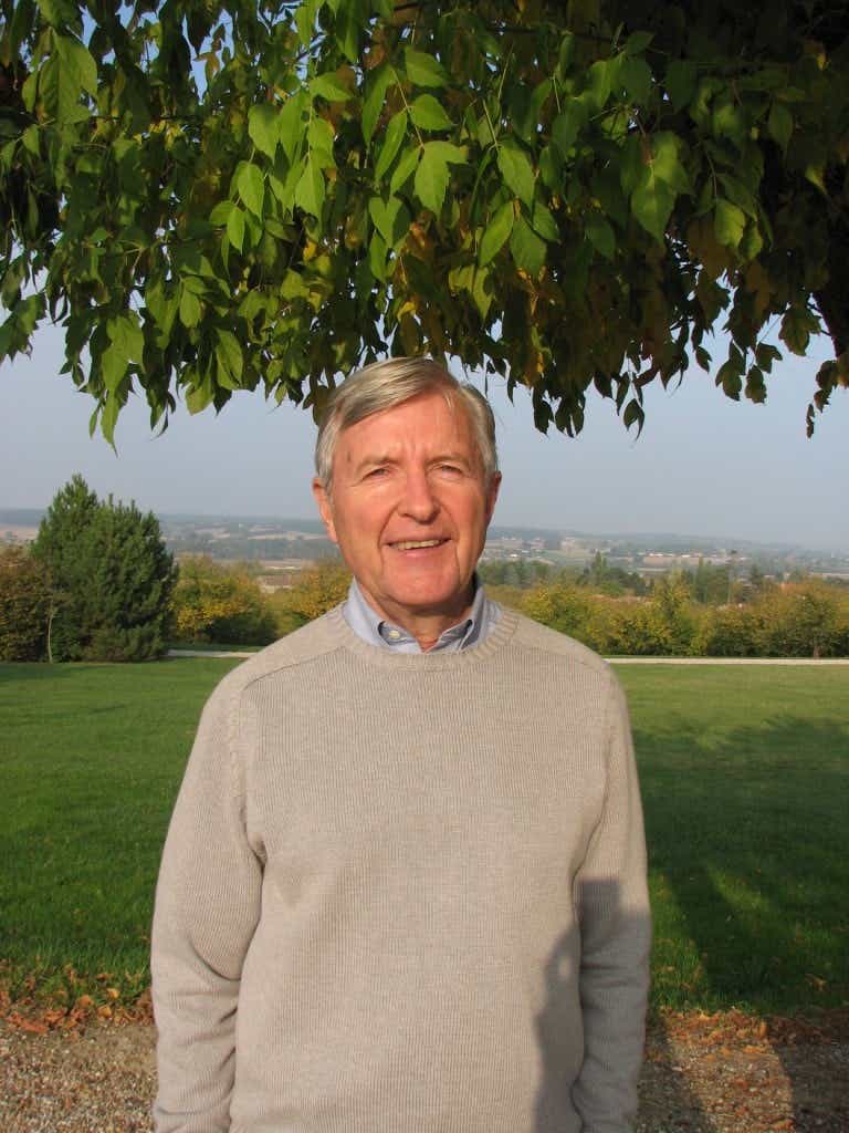 Michael Cooke smiles outside, surrounded by beautiful trees